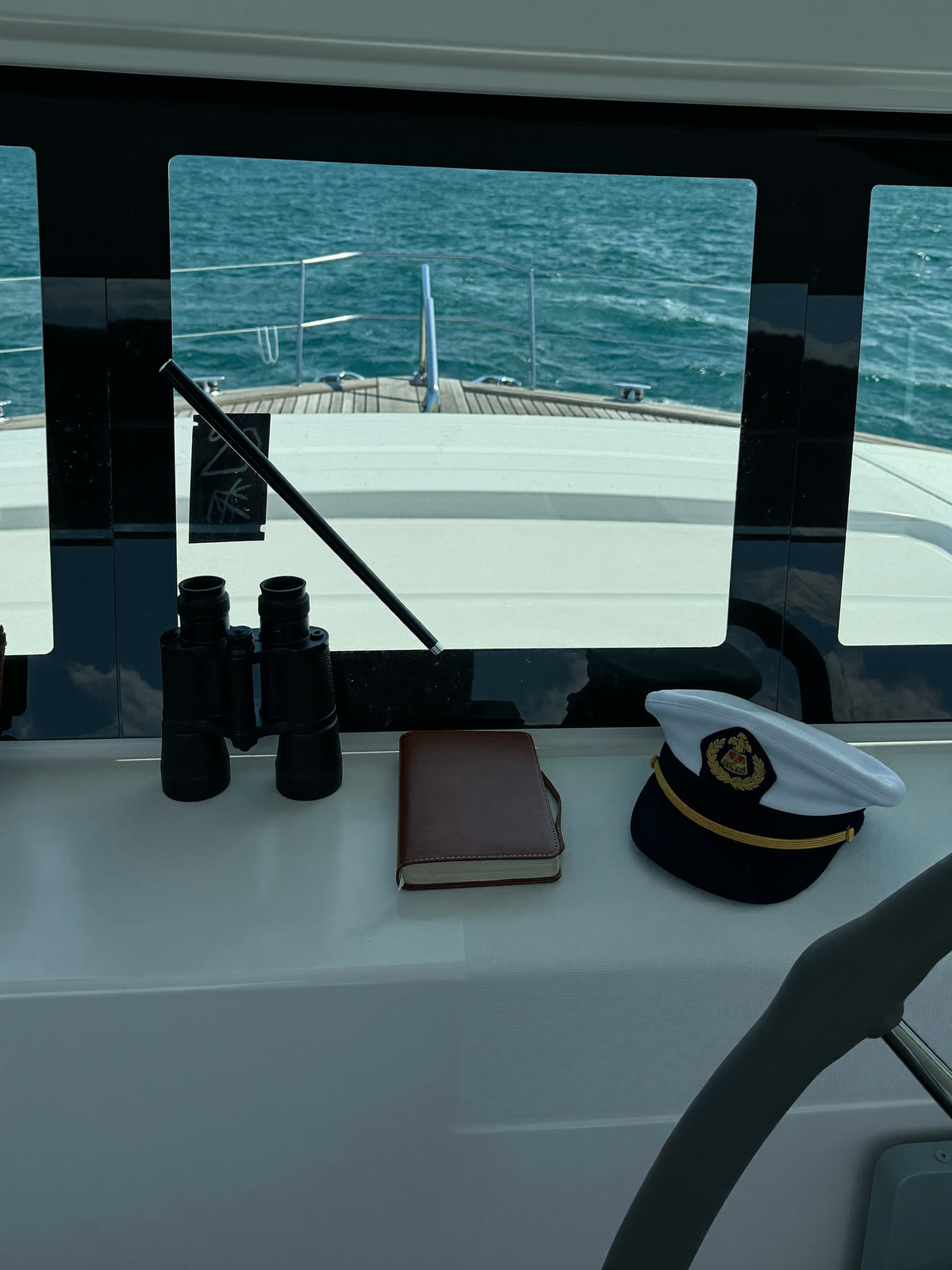 Binocolo, giornale di bordo e cappello sulla consolle di plancia