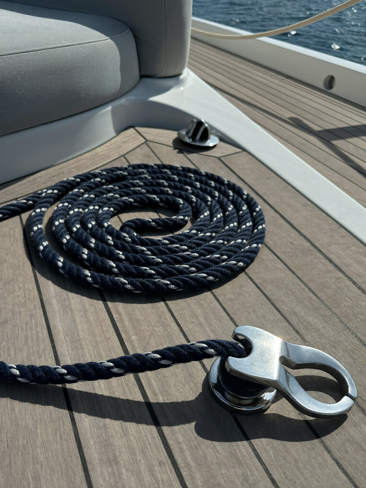 Cima d’ormeggio blu arrotolata sul ponte in teak di uno yacht