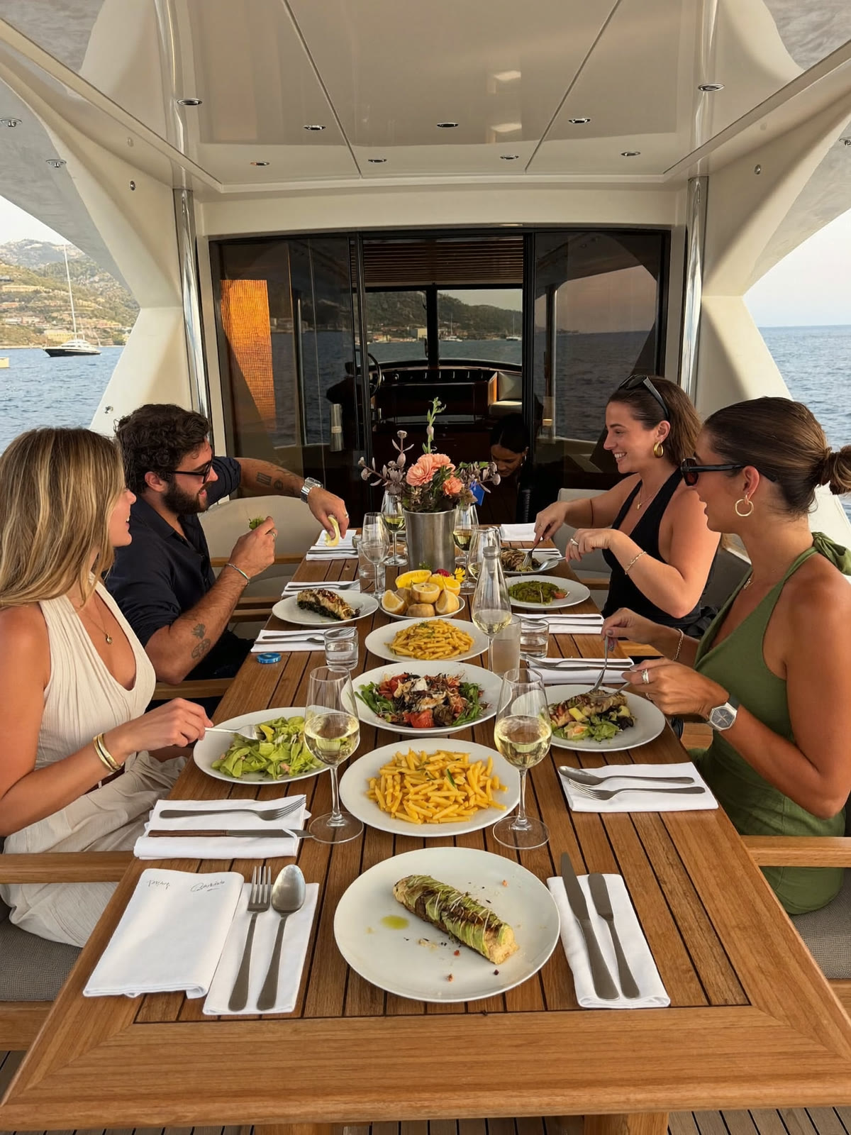 Ospiti a pranzo sul flybridge ombreggiato di uno yacht all’ancora