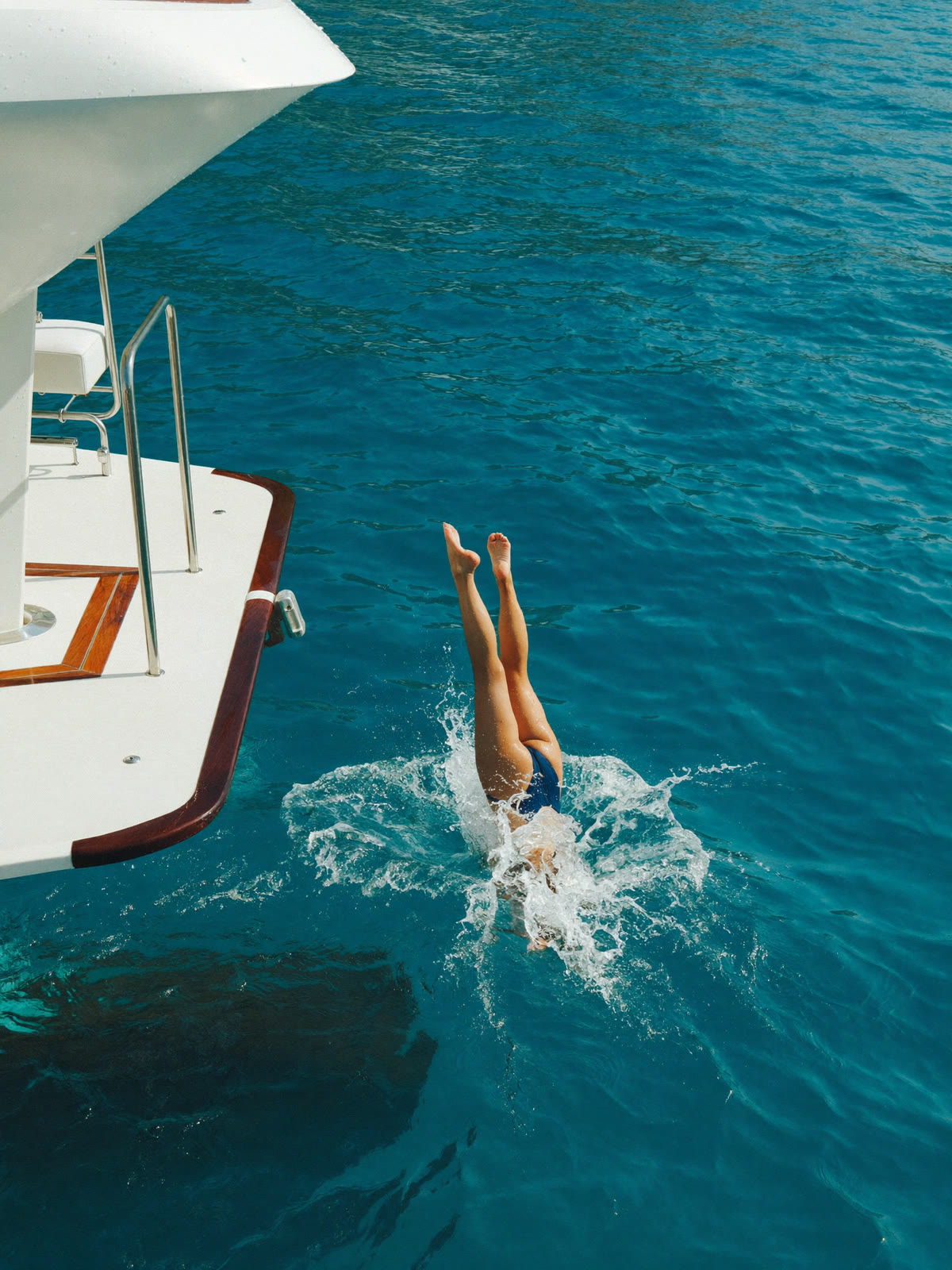 Tuffo dalla piattaforma di poppa di uno yacht nell’acqua turchese