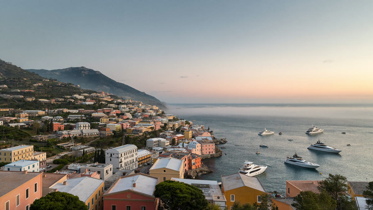 Borgo della costa ligure all’alba, con yacht all’ancora nella baia