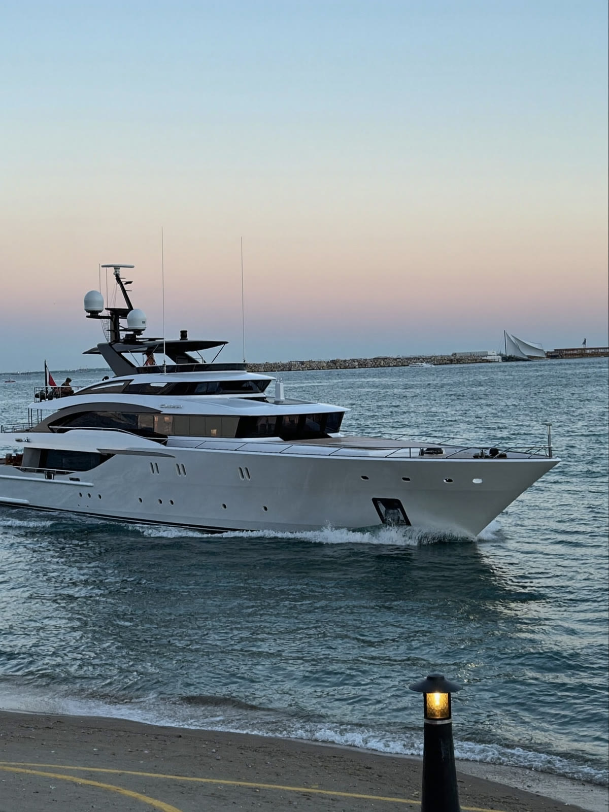 Yacht a motore che entra in porto all’alba, visto dalla diga foranea